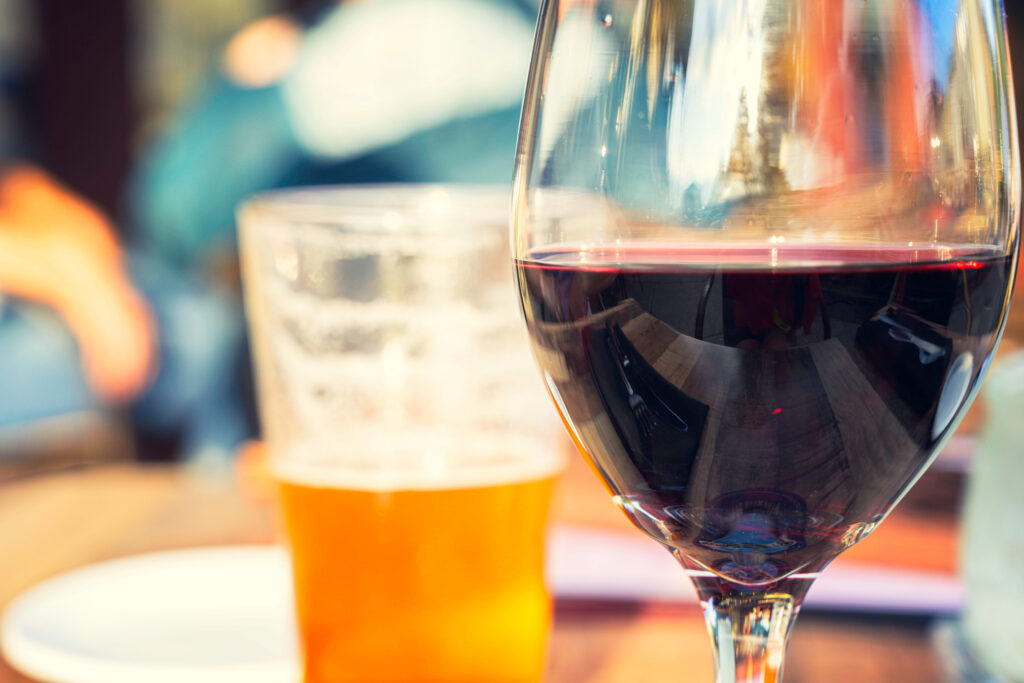 Red,Wine,And,Beer,Glass,On,Wooden,Table,With,Blurry